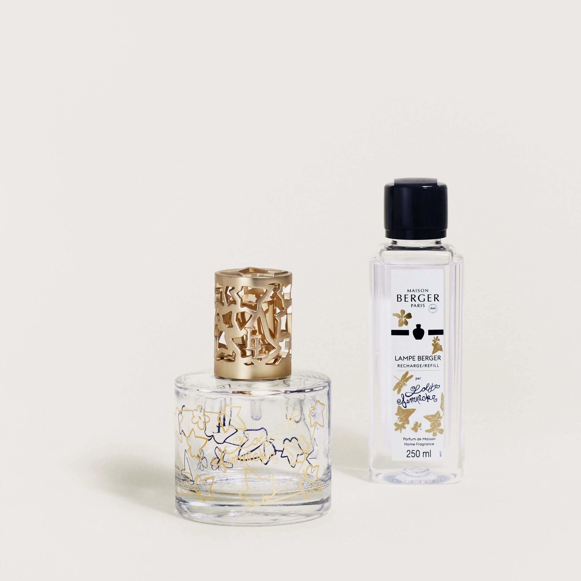 A Maison Berger fragrance lamp with a golden ivy leaf design on the top, accompanied by a bottle of fragrance fuel.