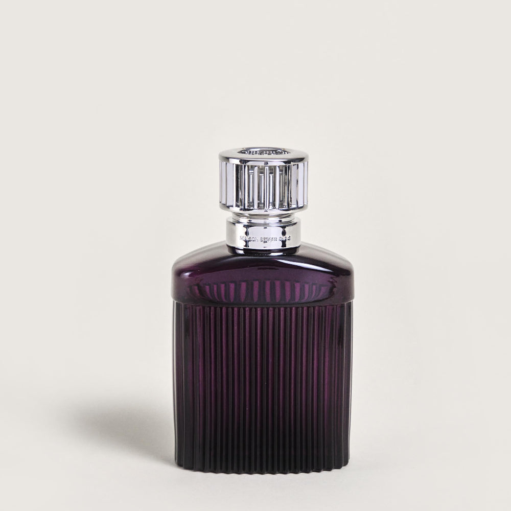 Purple perfume bottle with silver cap on a light beige background