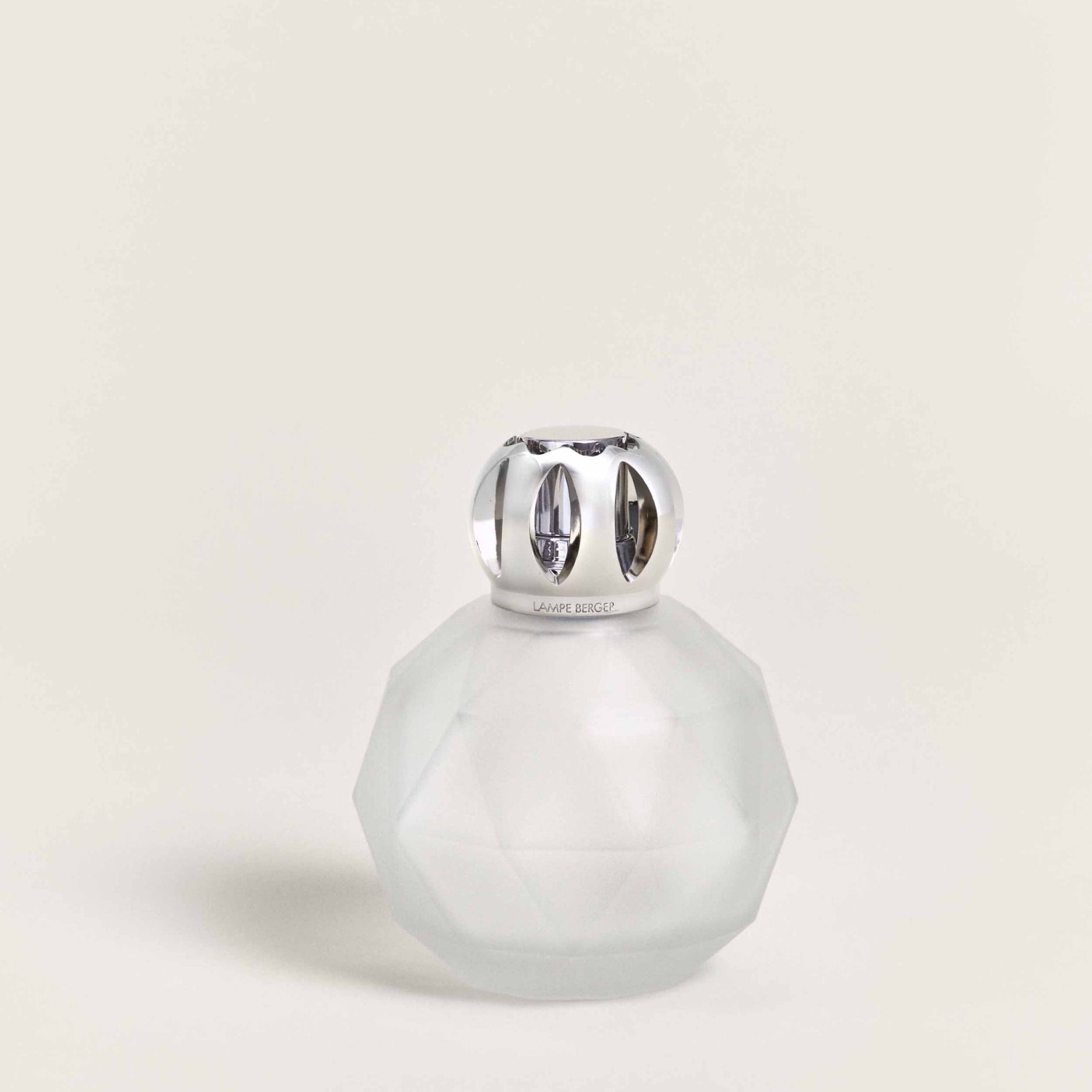 Frosted glass bottle with silver cap on a light beige background