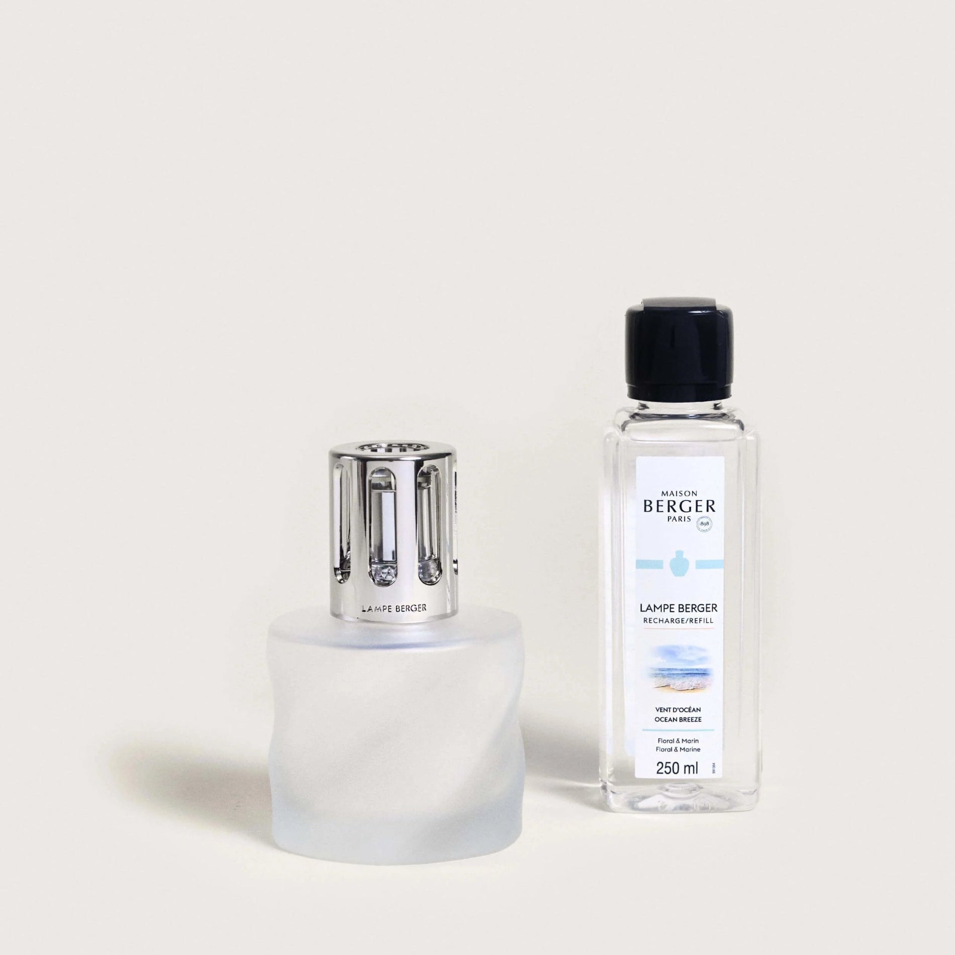A Maison Berger Paris Spirale Frosted fragrance lamp with a white base and a clear bottle of fragrance fuel.