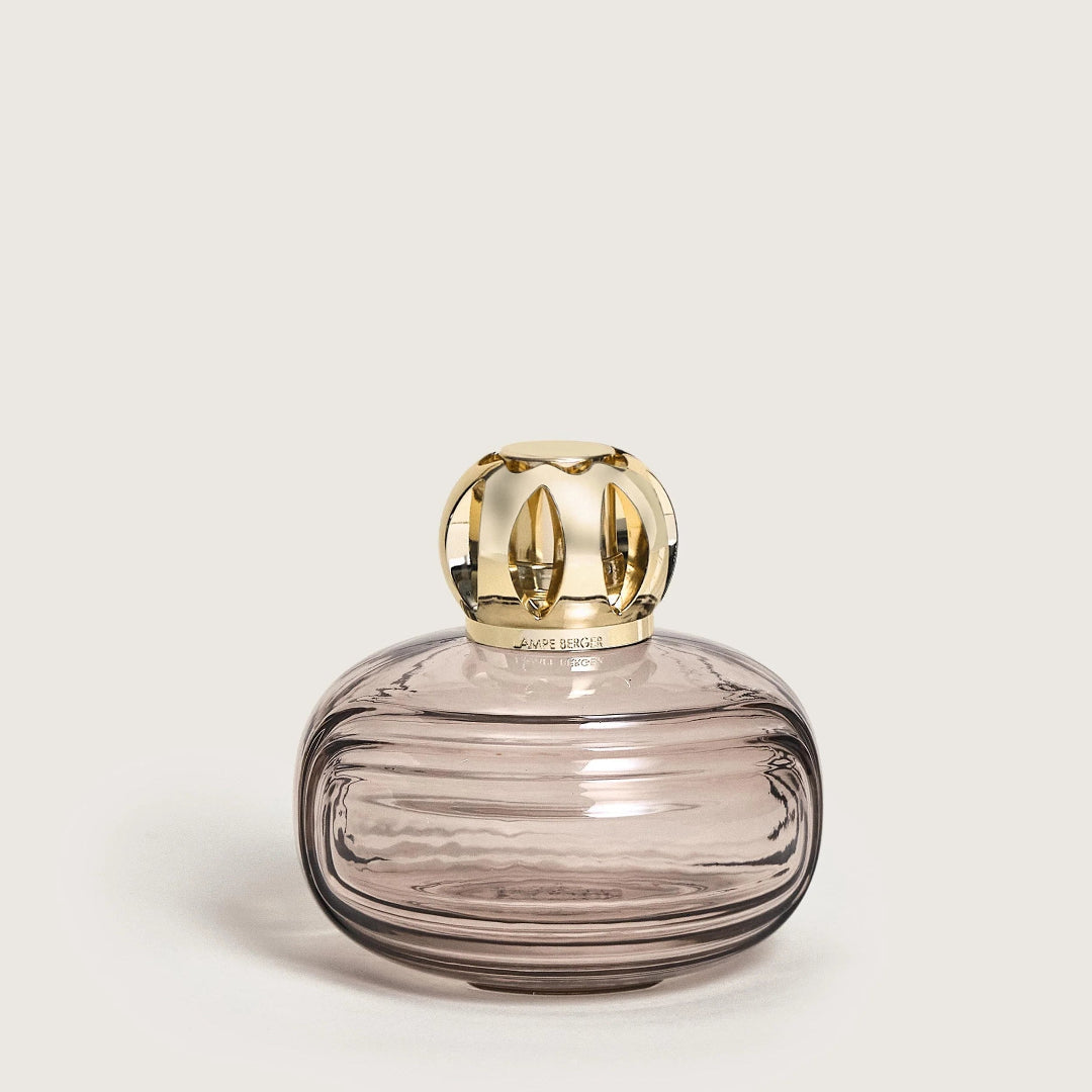 Glass container with gold lid on a light beige background