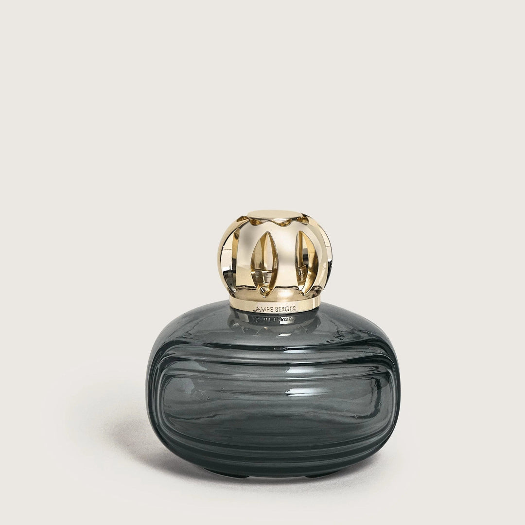Gray glass perfume bottle with gold cap on a light beige background