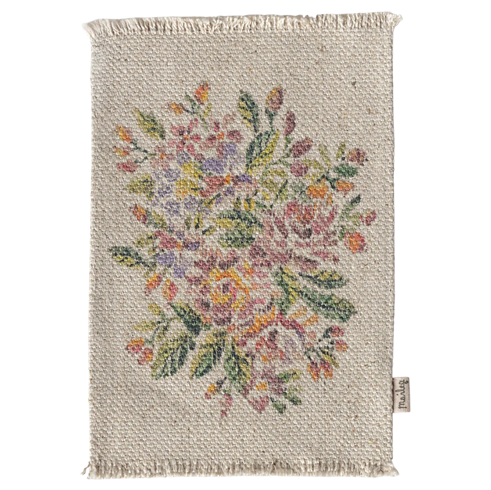 A small rectangular rug with a floral pattern in the center, predominantly featuring pink, yellow, and green colors.