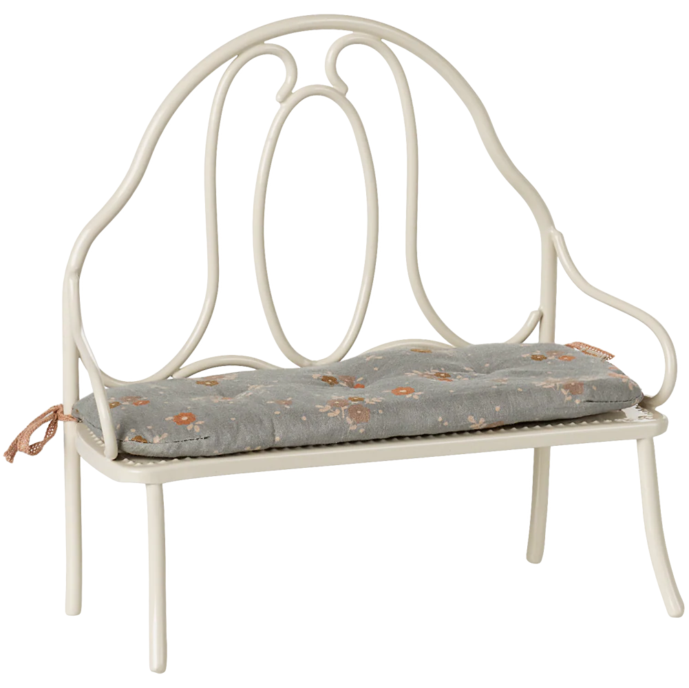 White metal bench with a floral cushion on a white background