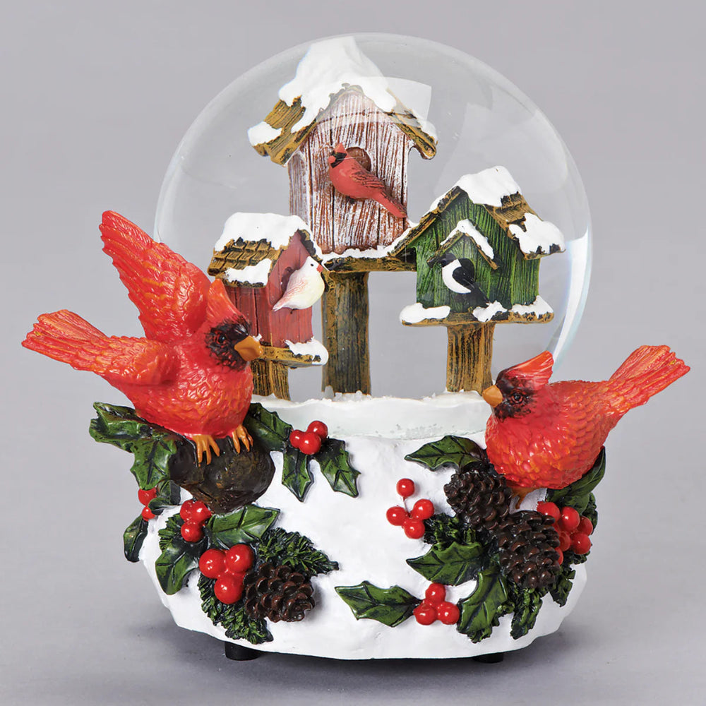 Decorative snow globe with cardinals, birdhouses, and holly decorations on a gray background
