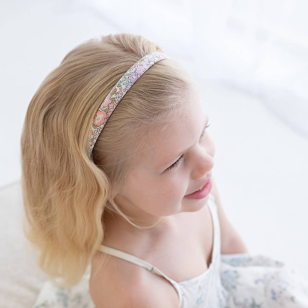 Young girl wearing a decorative headband with a soft white background