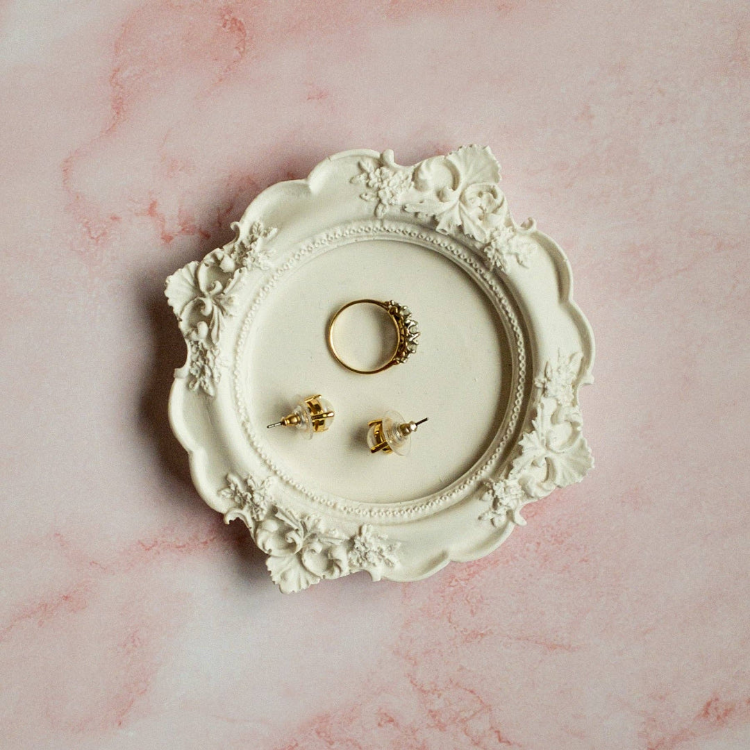 Decorative dish with jewelry on a pink marble surface