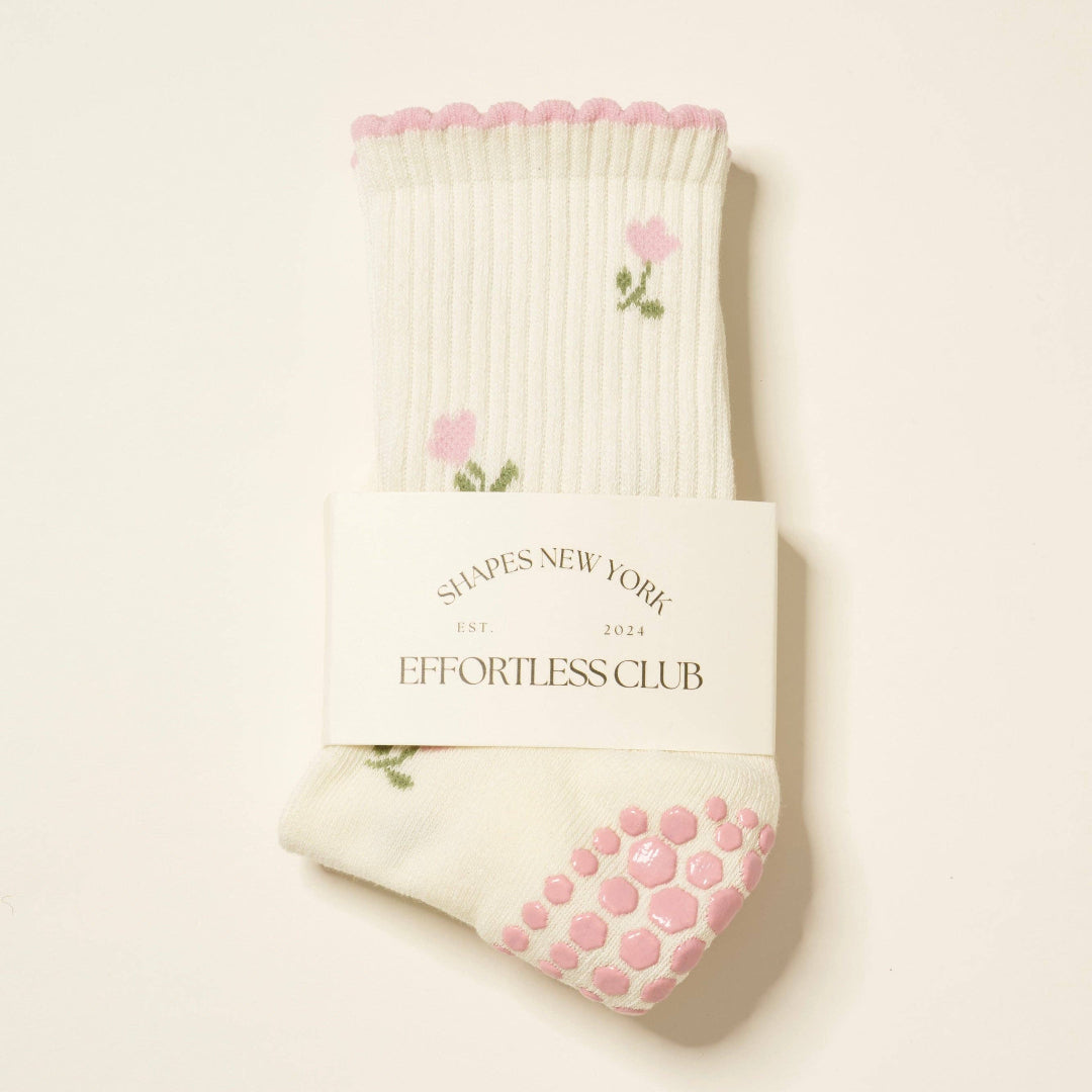 Cream-colored sock with pink grip dots and floral design on a white background