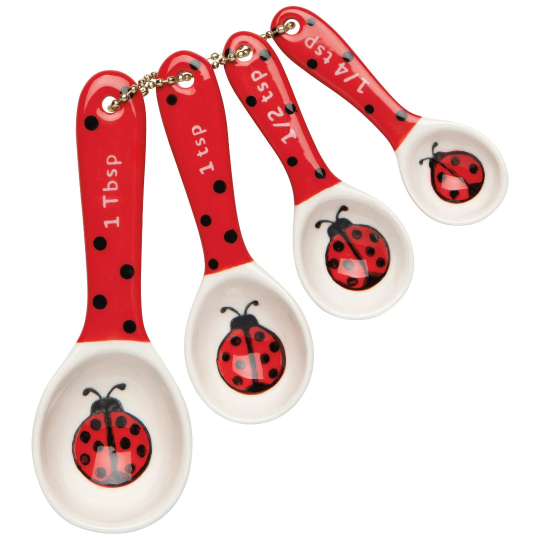 Set of four red and white measuring spoons with ladybug designs on a white background