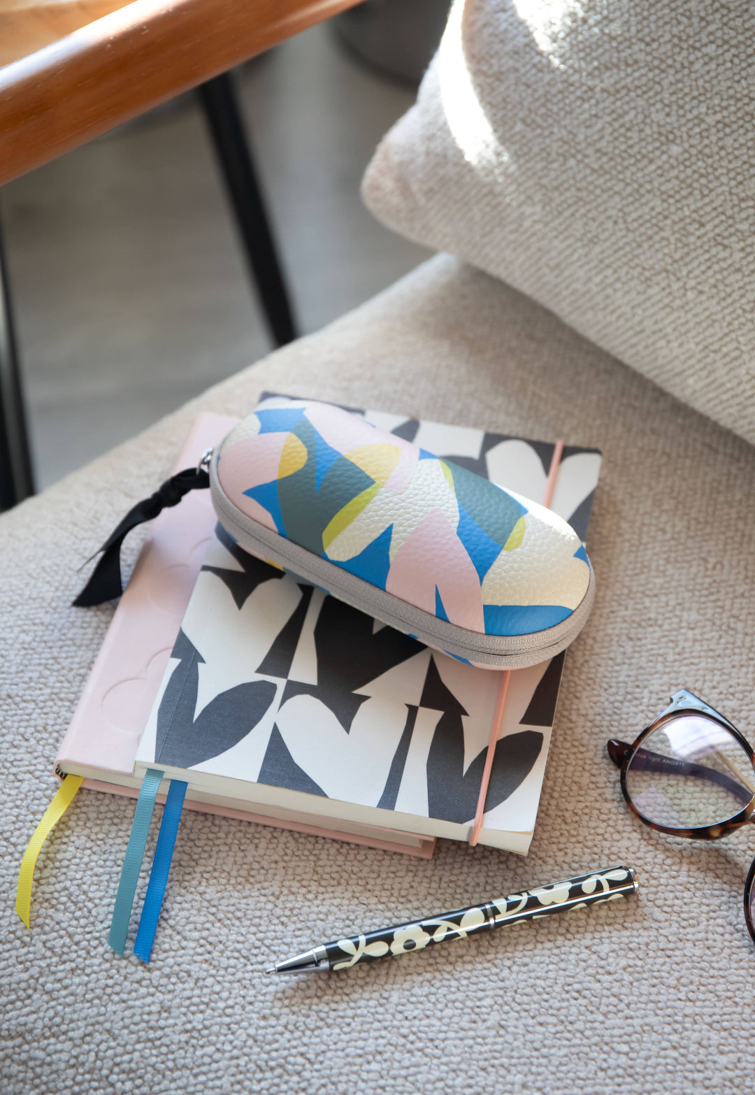 Colorful case on a notebook with a pen and glasses on a textured surface