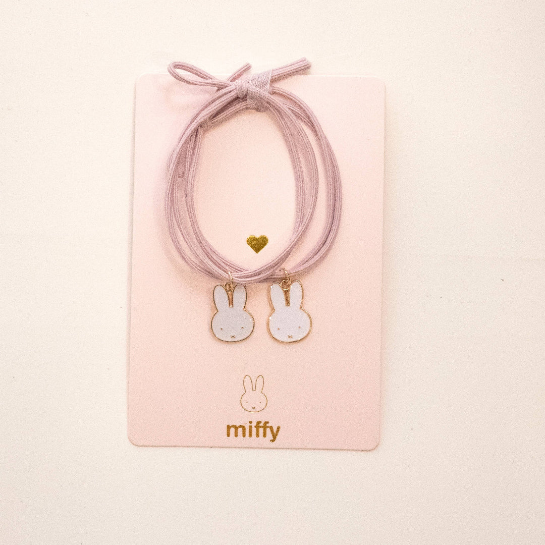 Pink hair ties with bunny charms on a pink card featuring the brand 'miffy'.