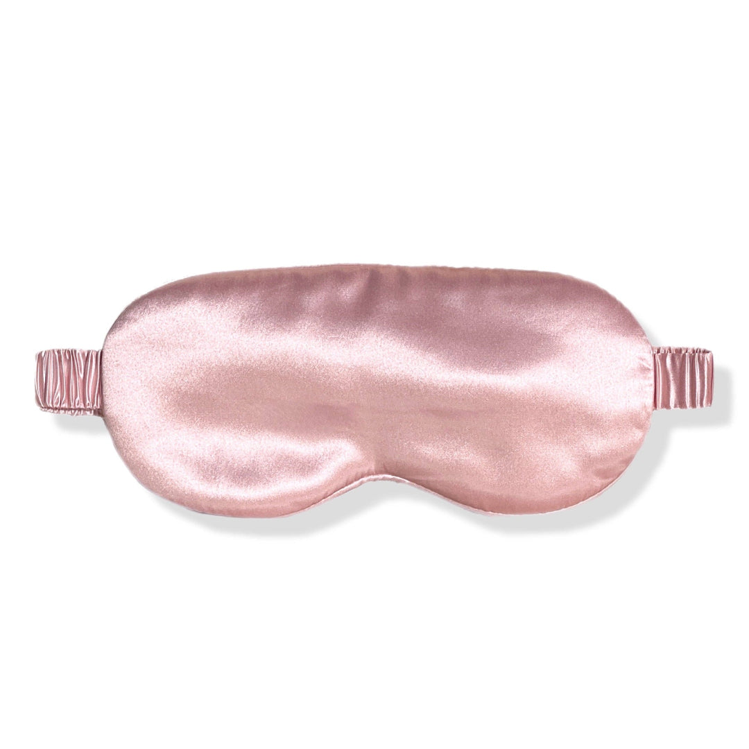 A pink premium organic silk sleep mask with a satin ribbon attachment.