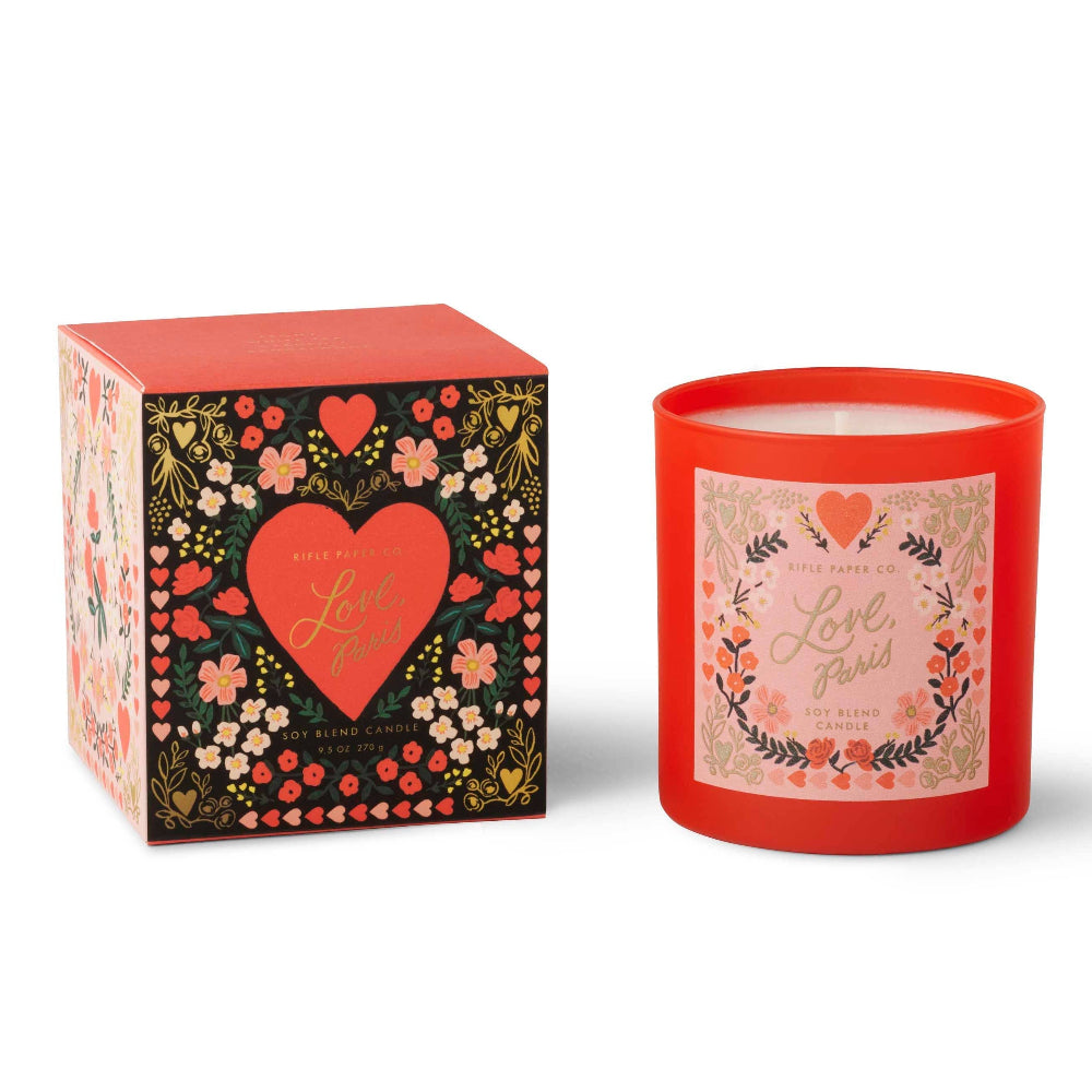 Red candle with floral design and matching box on a white background