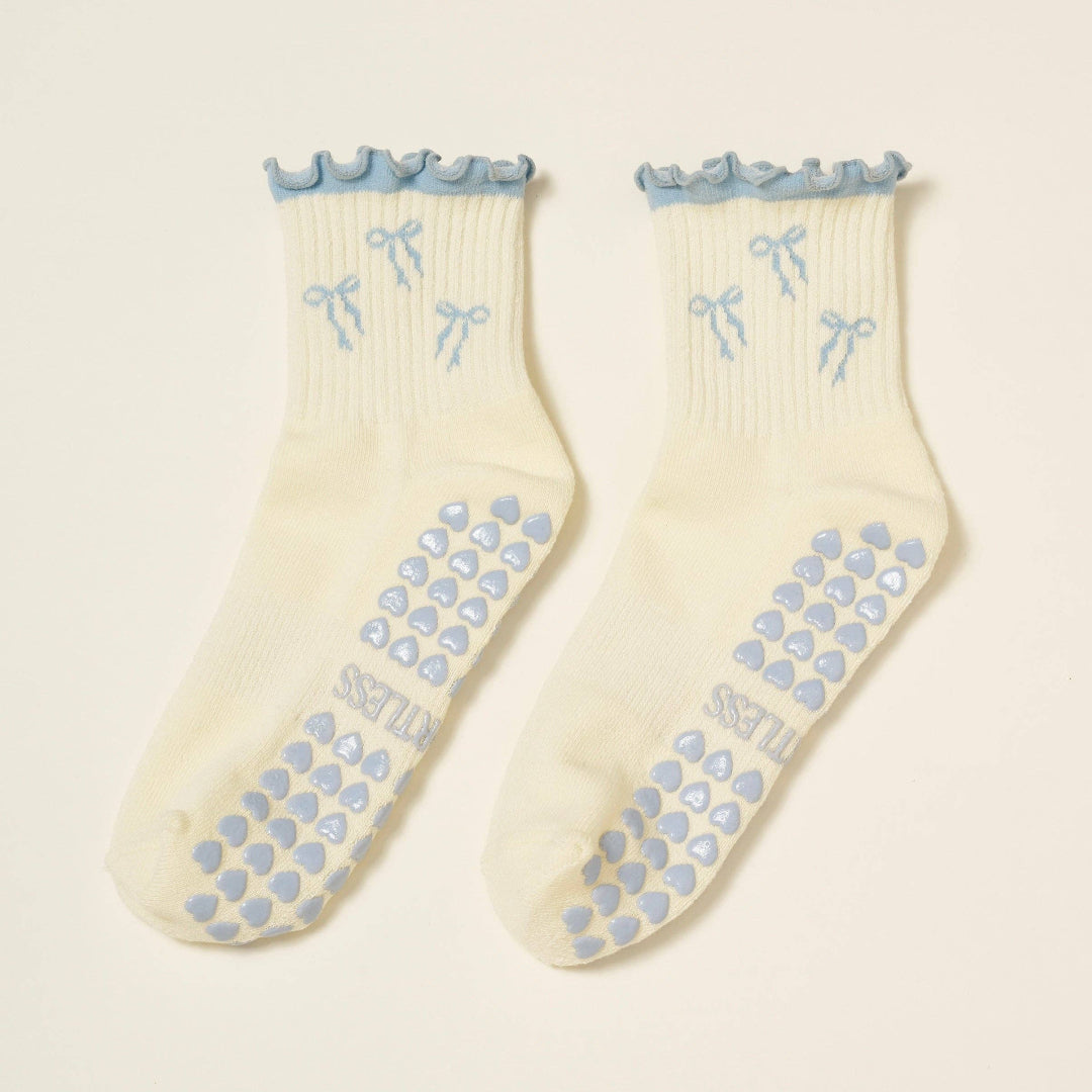 Pair of cream socks with blue bows and patterns on a beige background
