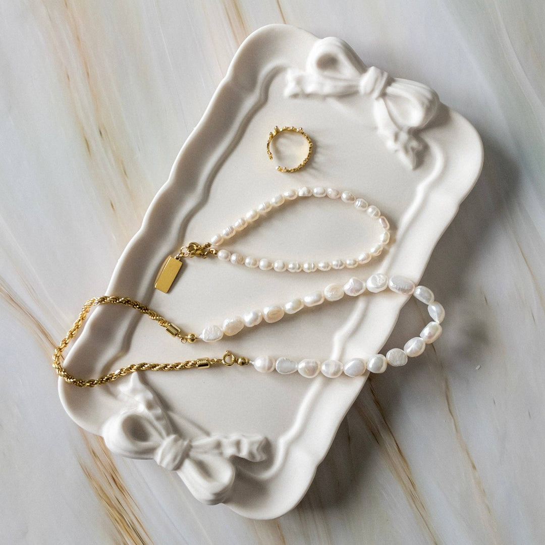 Jewelry set including a necklace and ring on a decorative white tray with bow design.