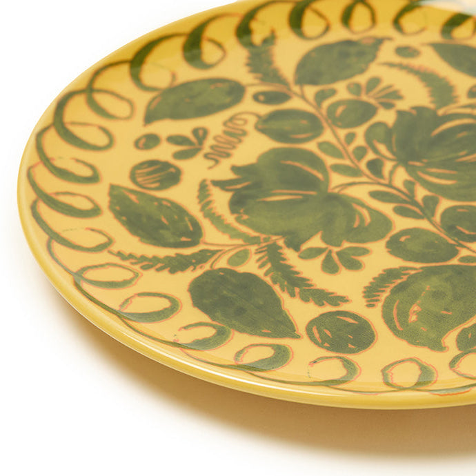 Decorative yellow plate with green floral pattern on a white background