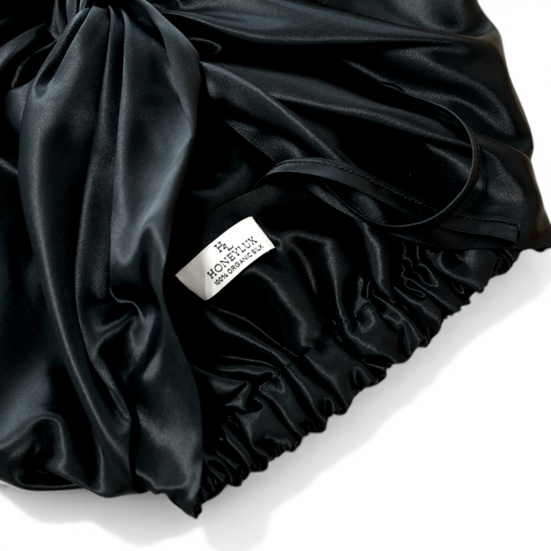 Black silk hair bonnet with 'HONEYLUX' 100% Oraganic Silk label on a light background