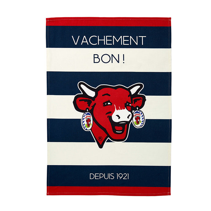 A blue and white striped cotton tea towel with 'VACHEMENT BON!' and a cartoon cow's face printed on it, along with the text 'DEPUIS 1921'.