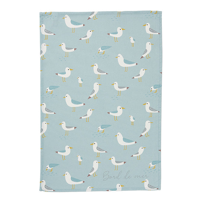 A blue cotton tea towel with a pattern of seagulls in various poses.