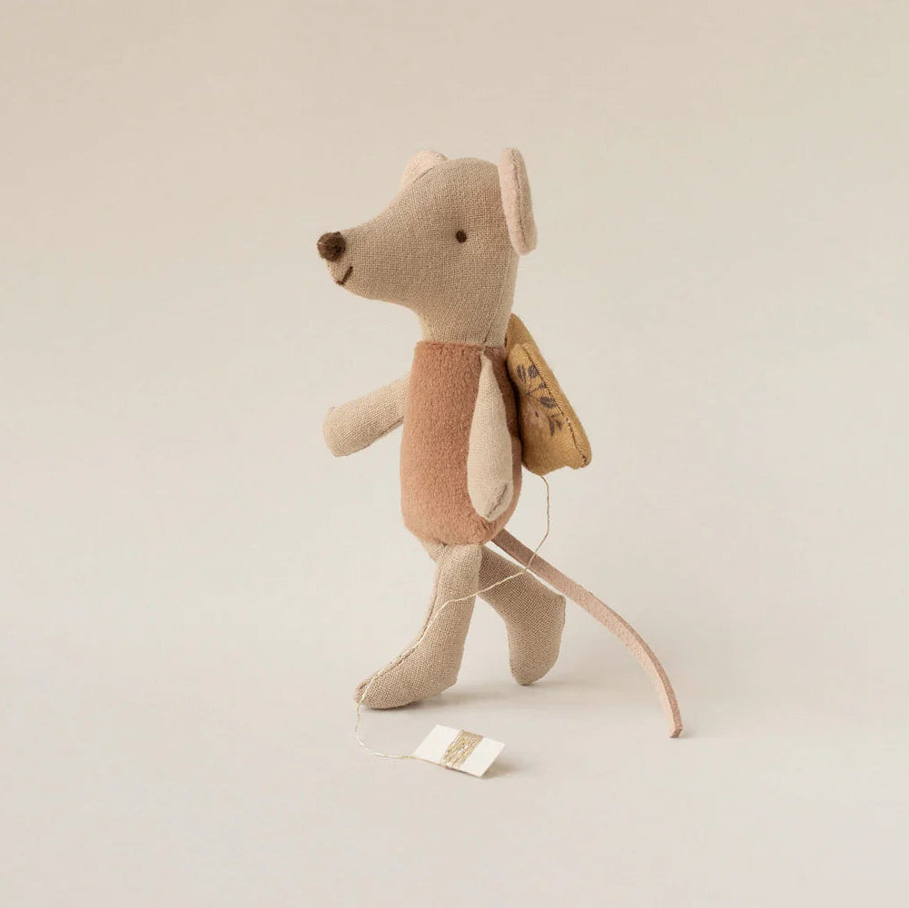 Stuffed mouse toy with a backpack on a beige background