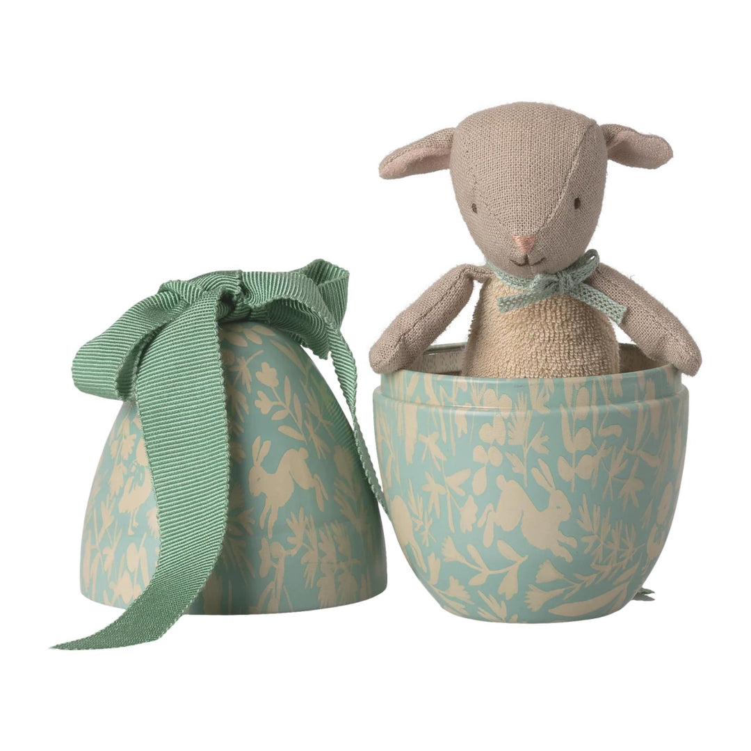 Small stuffed lamb toy in a tin egg shapedd box with a matching green ribbon on a white background