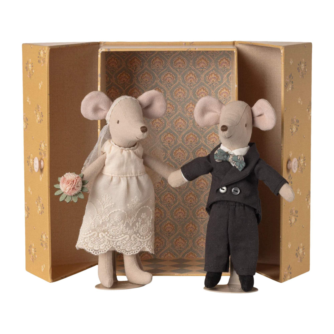 Two toy mice, one in a wedding dress and the other in a suit, standing in front of a closet box