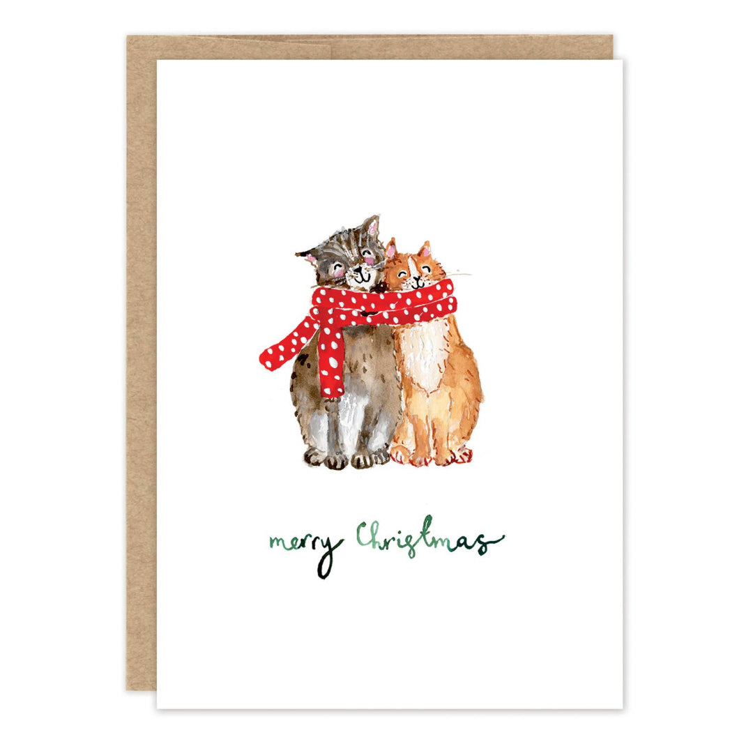A Christmas greeting card with a kraft envelope behind it, featuring an illustration of two cats wrapped in a red polka-dot scarf, with the text 'merry Christmas' below.