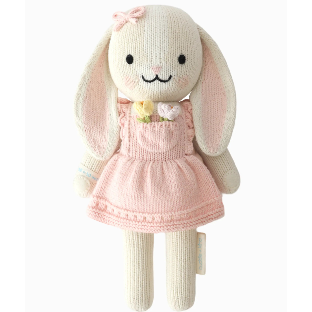 Knitted bunny toy with a pink dress on a white background