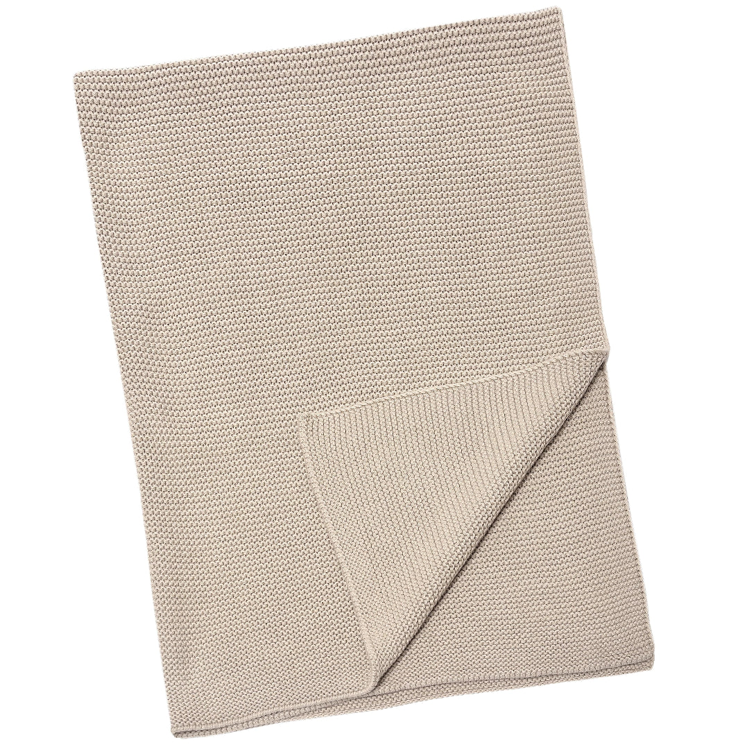 A beige, knit Ryan baby blanket laid out on a plain background.