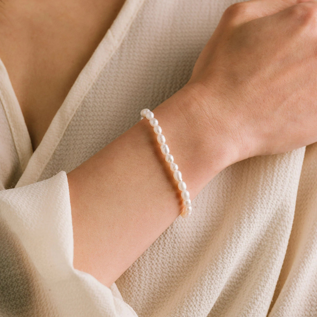 Pearl bracelet on a wrist with a neutral background