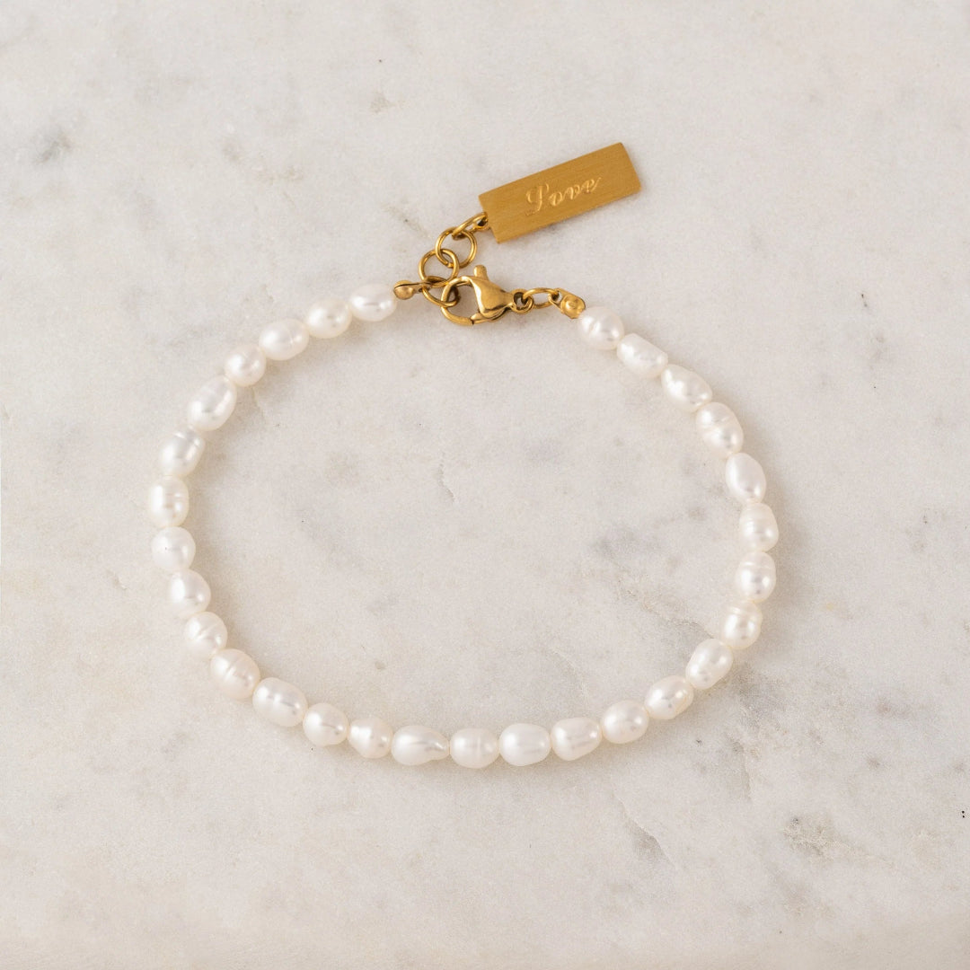 Pearl bracelet with gold clasp on a marble surface
