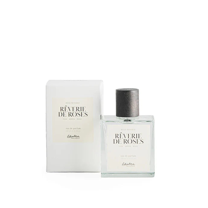 A bottle of Lothantique Eau de Parfum Rose Reverie with its packaging box. The bottle is clear and has a label with the product name, and the box is white with 'Rîverie de Roses' printed on it.