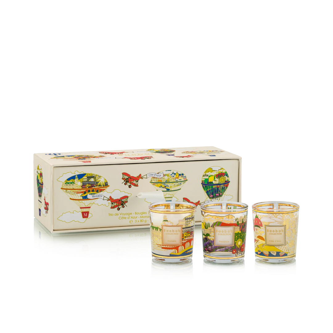 Set of three small candles with colorful designs in front of a decorative box on a white background