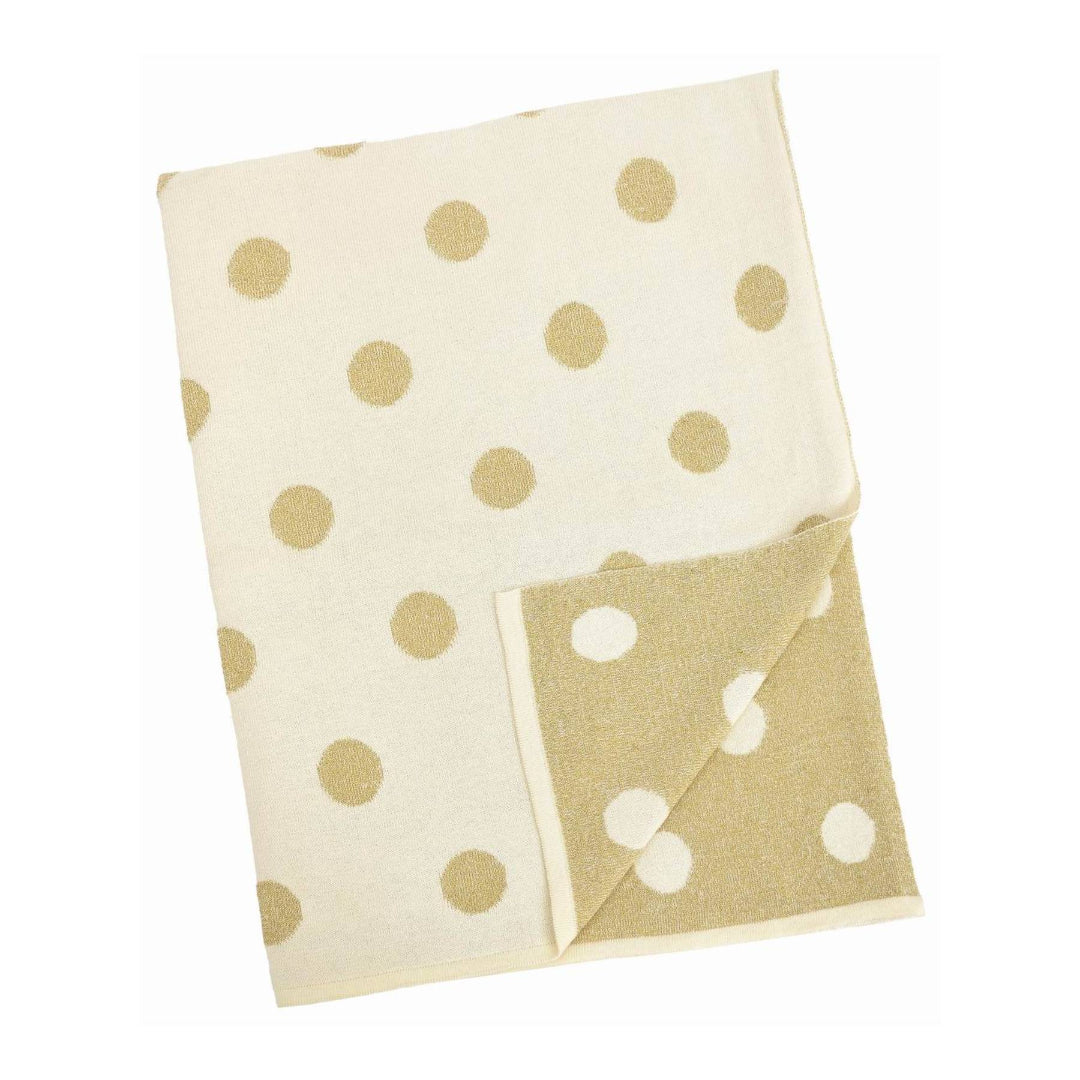 Folded blanket with gold polka dots on one side and white polka dots on the other, on a white background.
