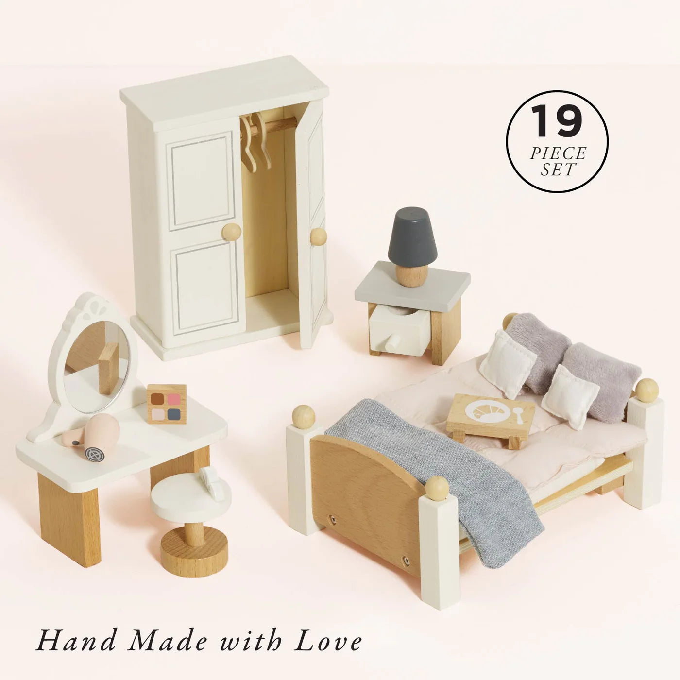 Wooden dollhouse furniture set with a bed, dresser, and vanity on a light pink background.