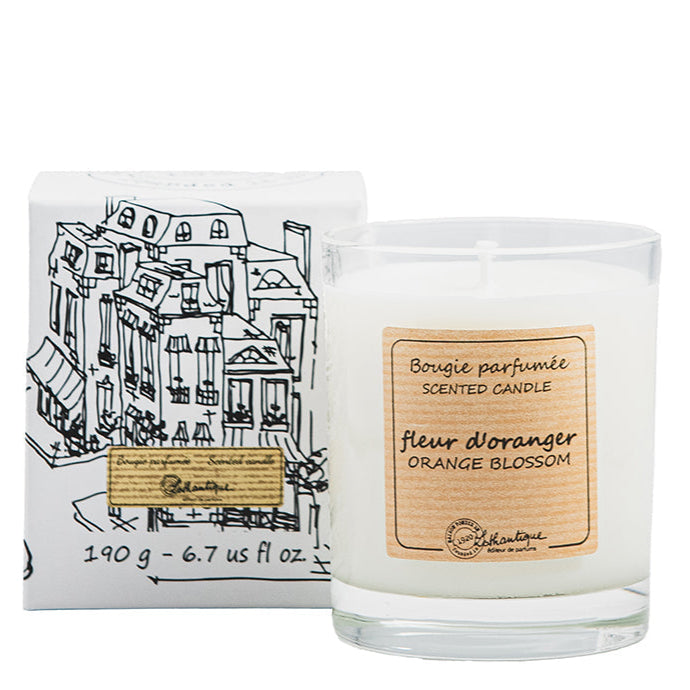 A white scented candle labeled 'Fleur D'Orangerie' Orange Blossom', with a drawing of a cityscape on the packaging.