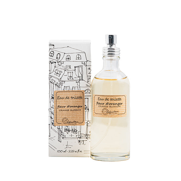 A bottle of Authentique Orange Blossom Eau de Toilette with a spray nozzle, accompanied by its packaging featuring a black and white illustration of a cityscape.