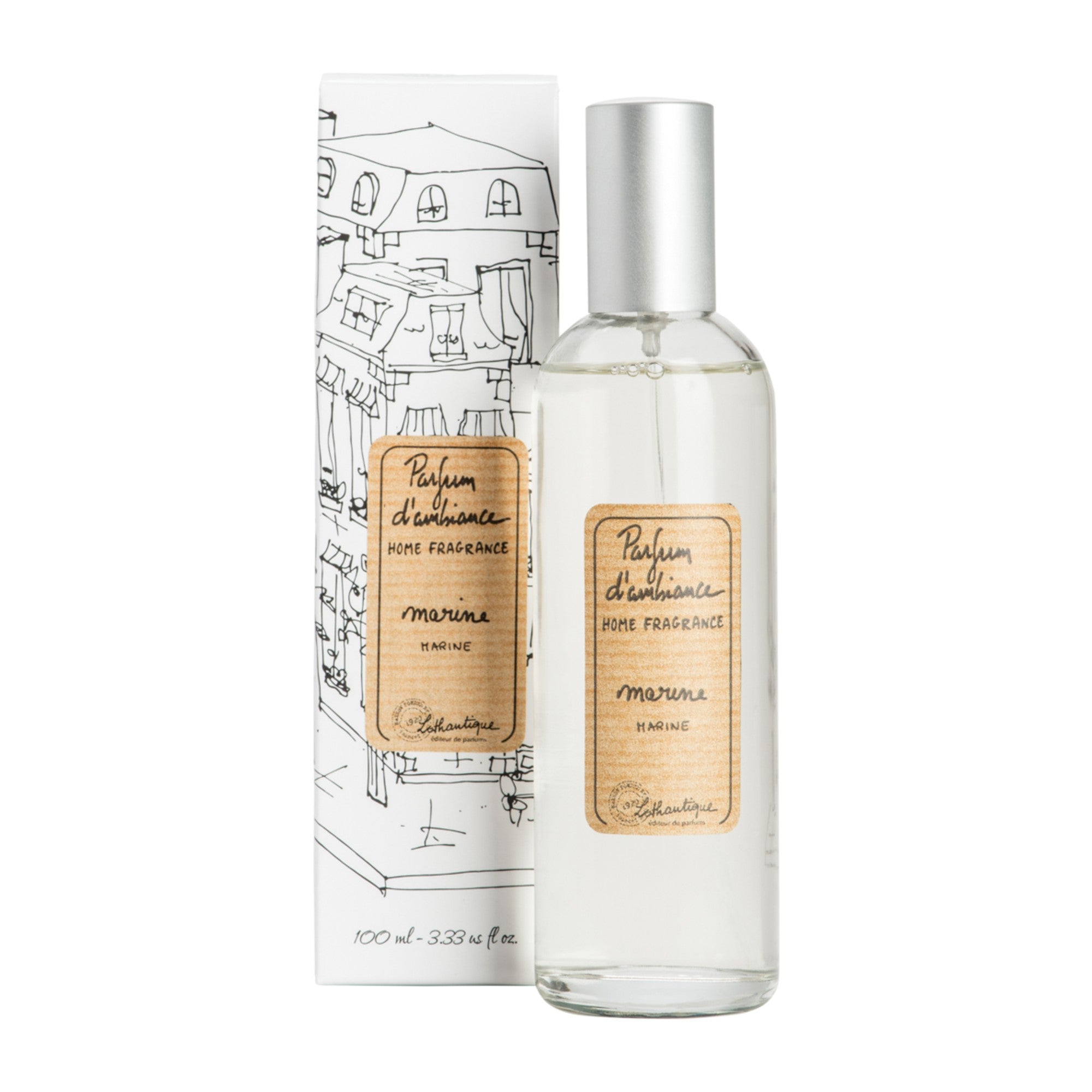 A clear glass room spray bottle with a label next to its packaging featuring a drawing of a house.