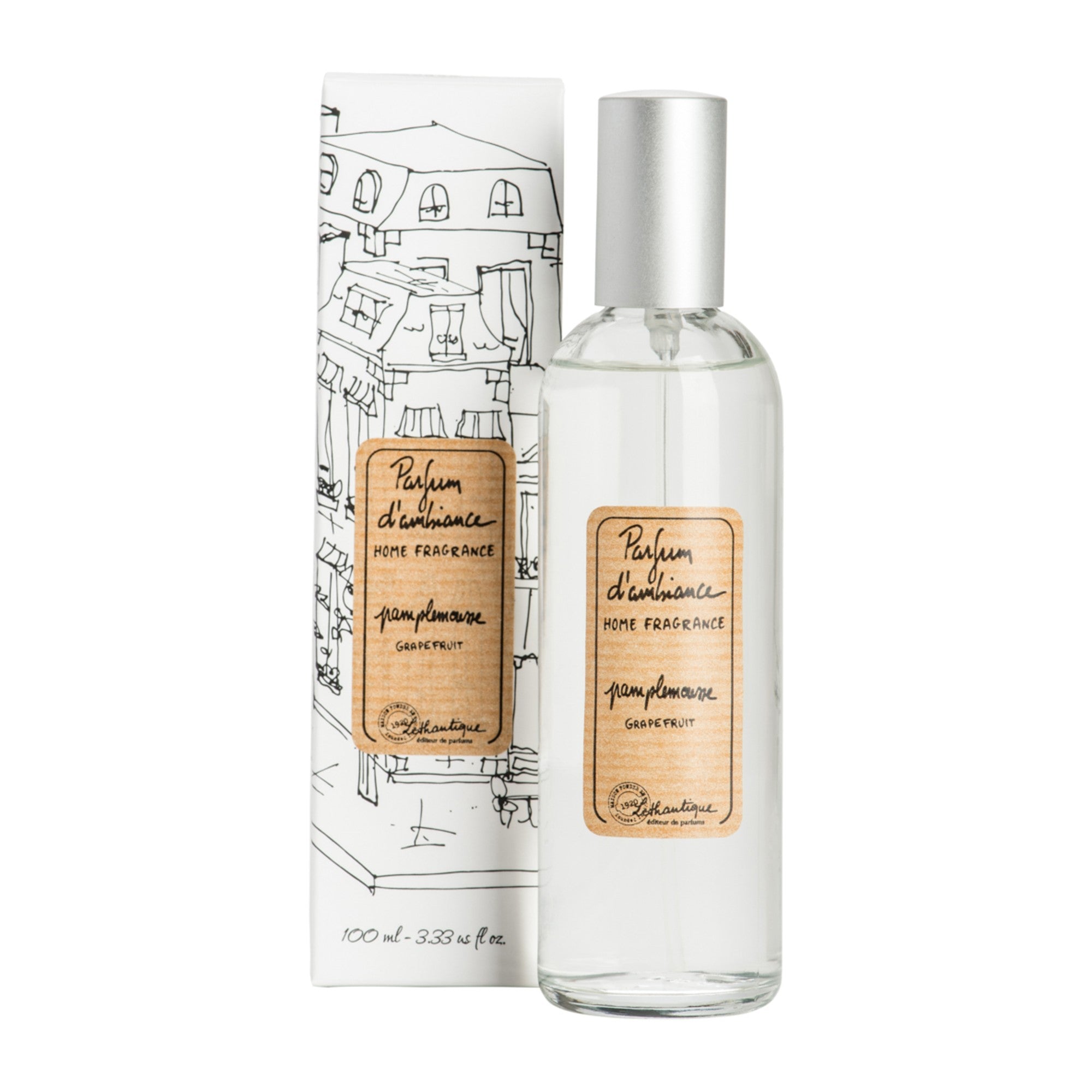 A clear glass room spray bottle with a label next to its packaging featuring a drawing of a house.