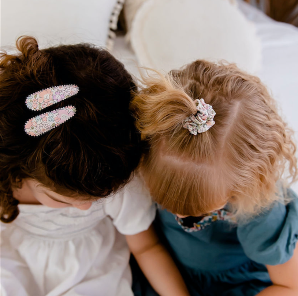 Two children with decorative hair accessories sitting close together.