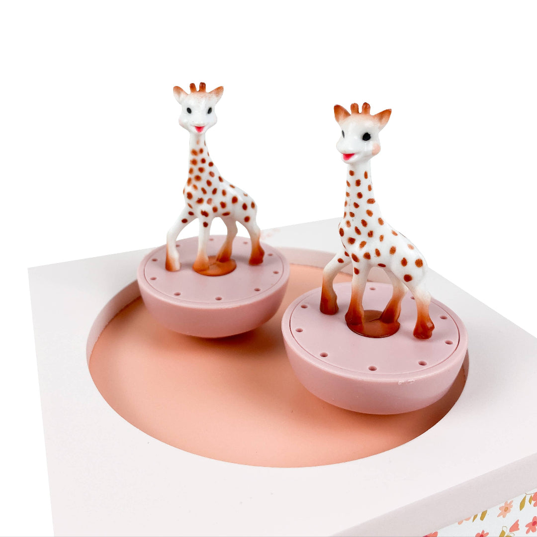 Two giraffe toys on pink stands with a white background