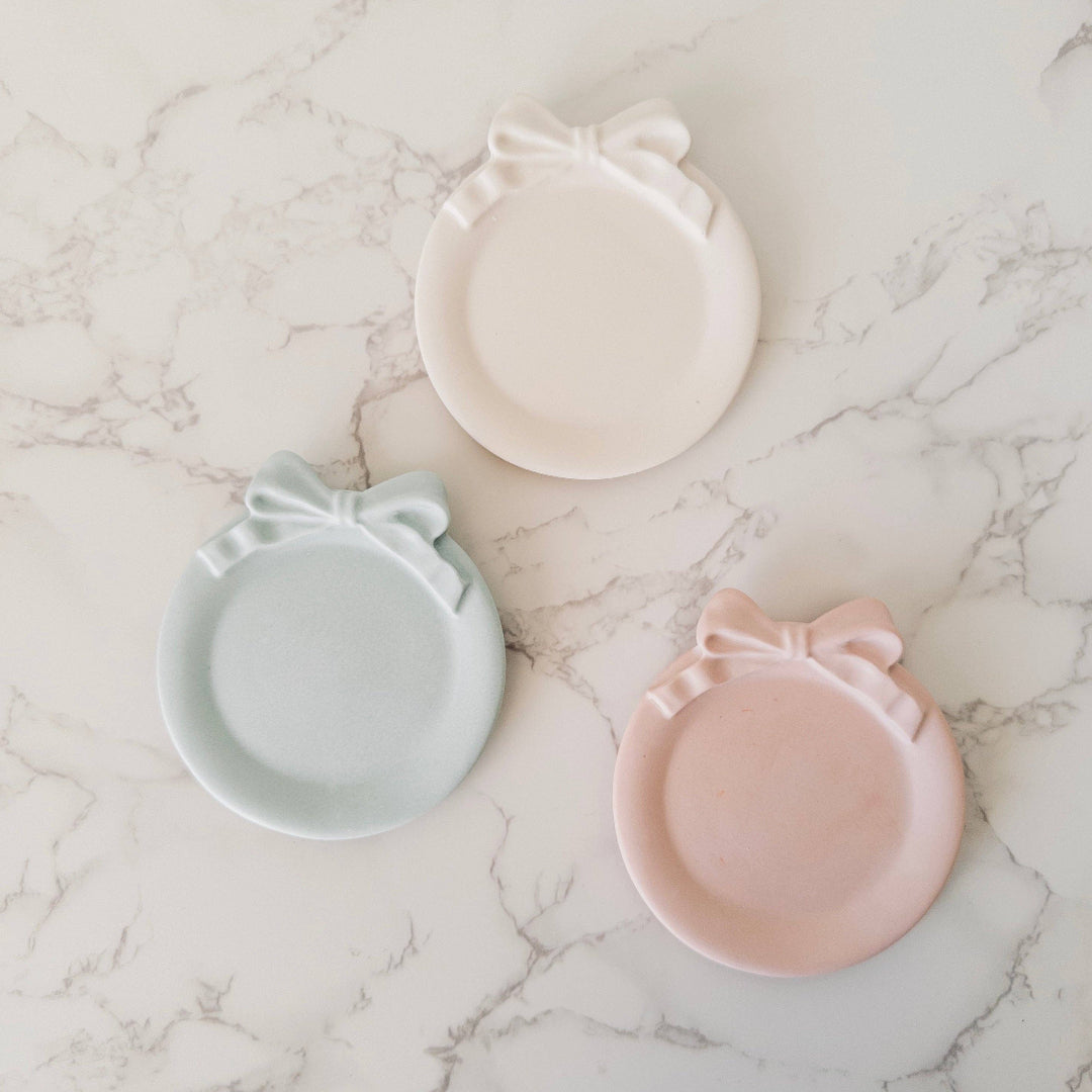 Three ceramic dishes with bows on a marble surface