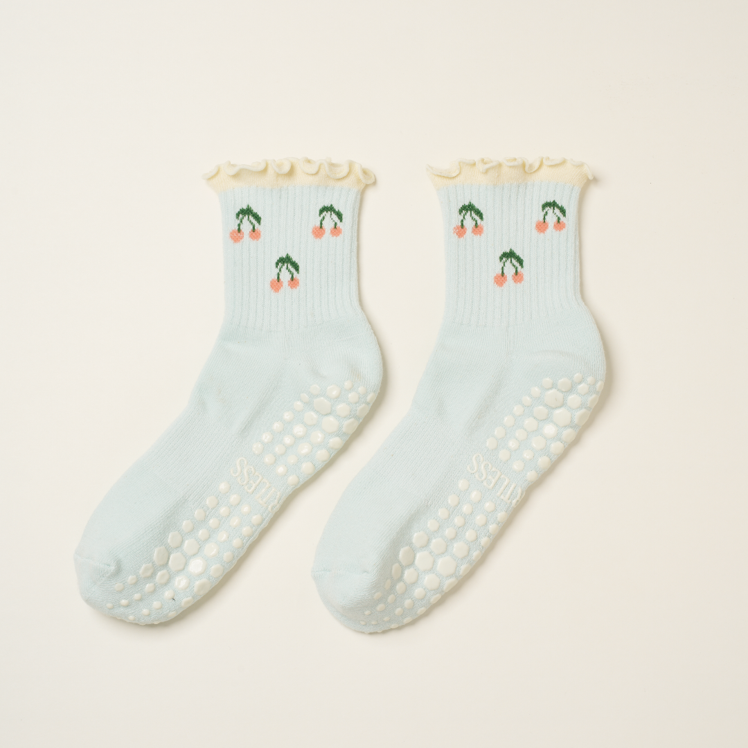 Pair of light blue socks with cherry design on a beige background