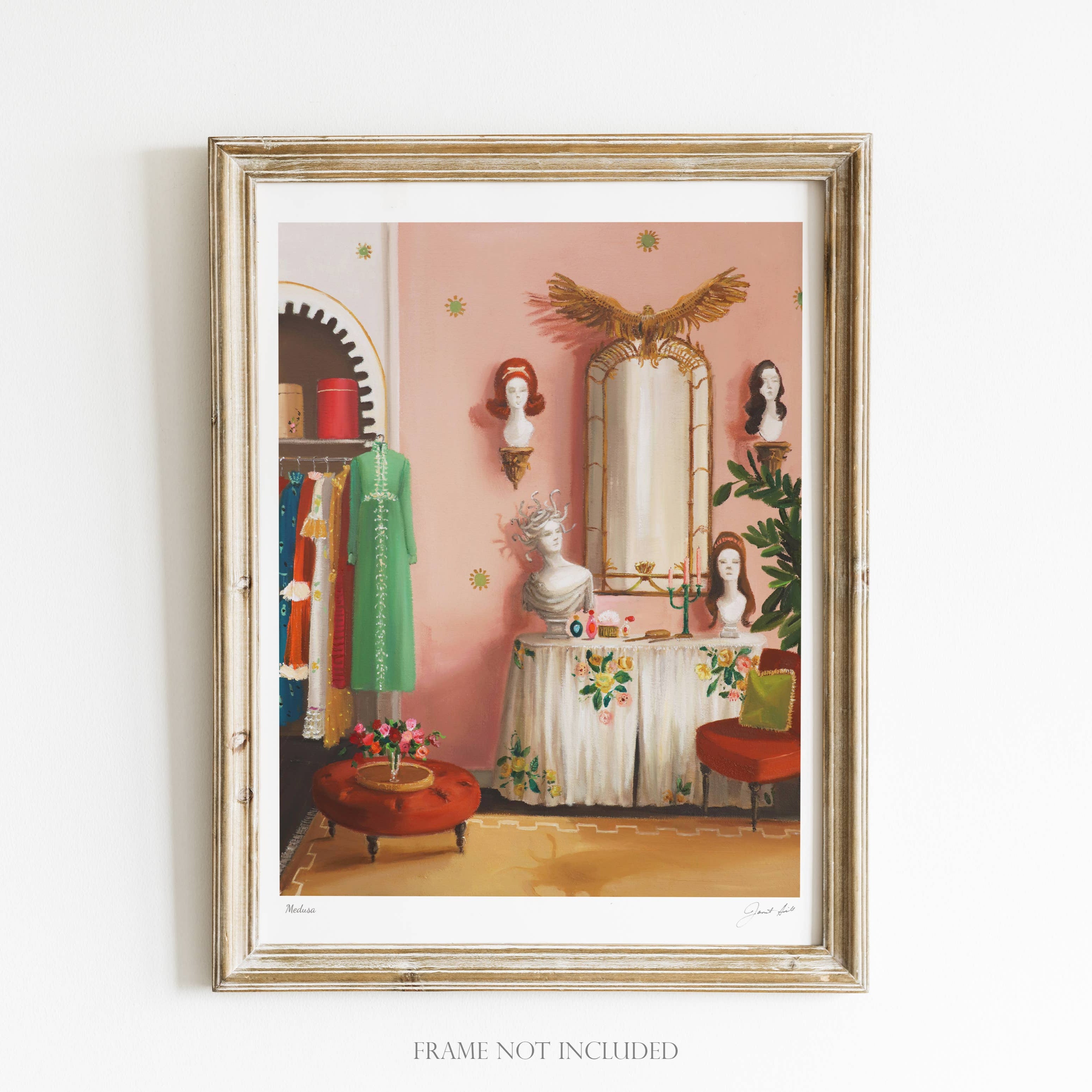 A framed art print featuring a whimsical scene with a mirror, dresses, and a decorative bird on a wall, indicating a vintage aesthetic. The frame is wooden and the artwork is signed by 'Janet Hill Studio'.