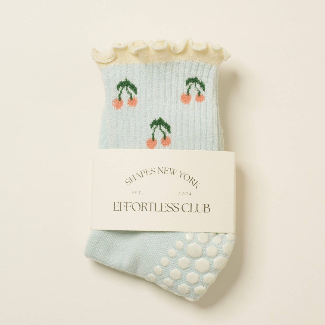 Pair of light blue socks with cherry design on a beige background