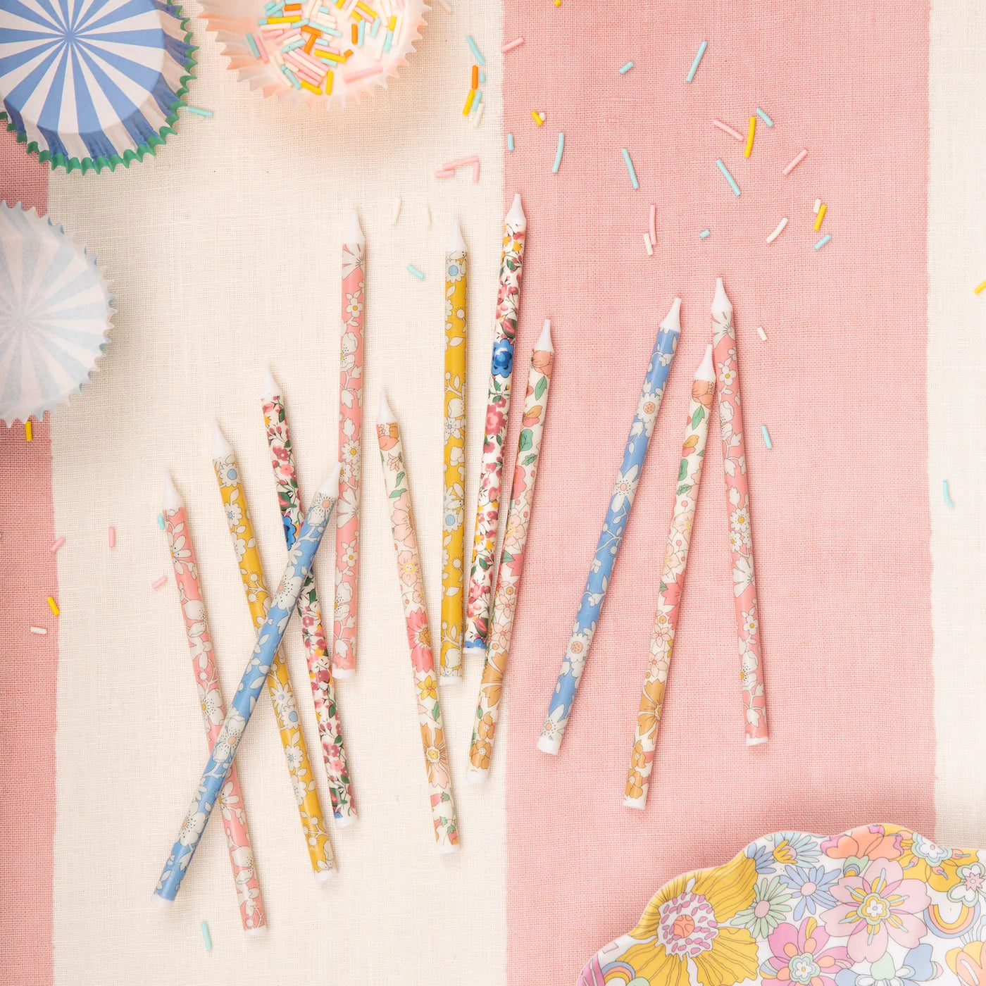 Decorative candles with floral patterns on a pink and white striped background