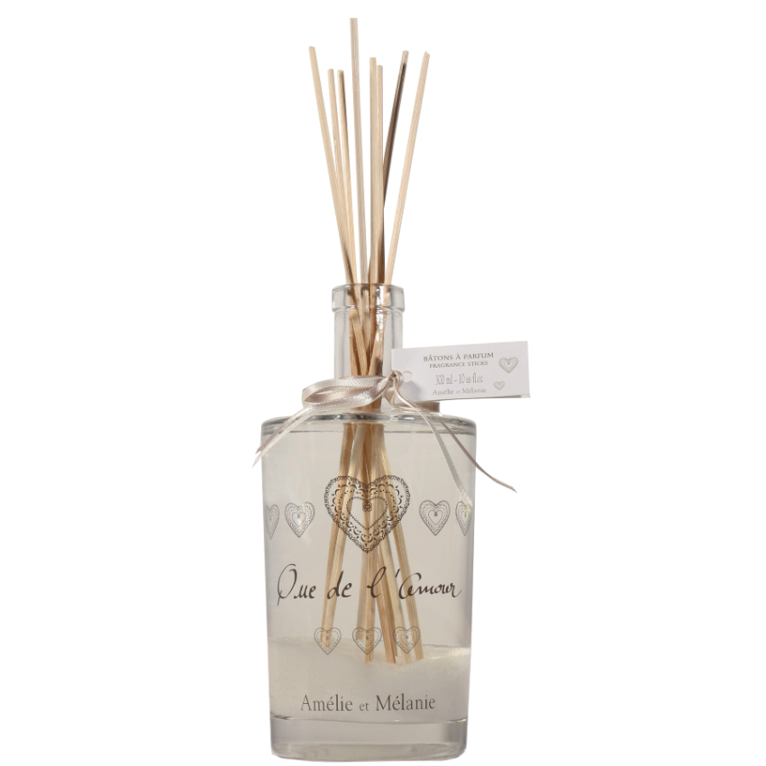 Clear diffuser bottle with wooden sticks and decorative hearts on a white background