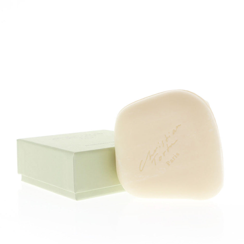 A bar of soap next to its green and white box, with the brand name 'Christian Tortu' inscribed on the soap.