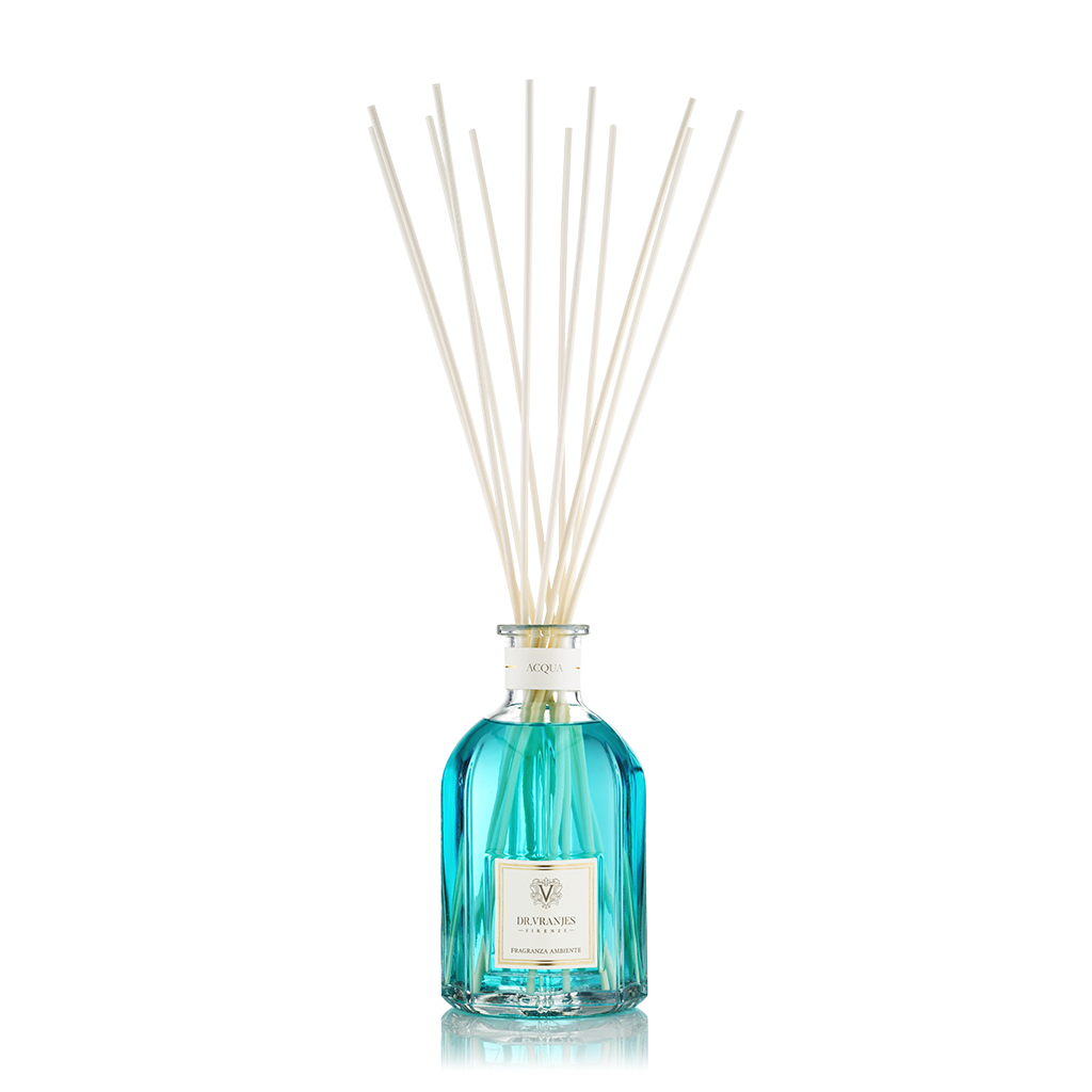A fragrance diffuser with clear glass bottle and blue liquid, topped with several white diffusing sticks.