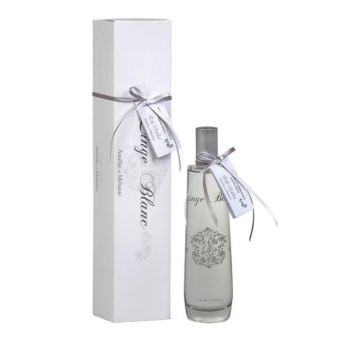 A white room spray bottle with a label and decorative elements, tied with a ribbon, alongside its white packaging box, also adorned with a ribbon.